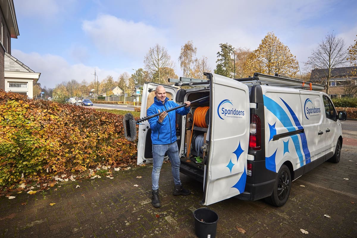 Sparidaens-bedrijfsbus bij een woning tijdens het met de hand schoonmaken van de dakgoot