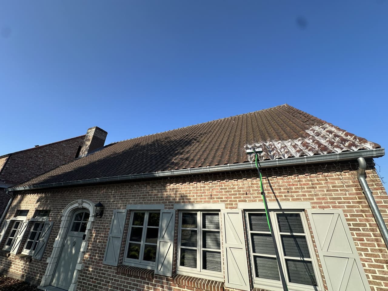 Dak in Hapert tijdens het verwijderen van mos en aanslag
