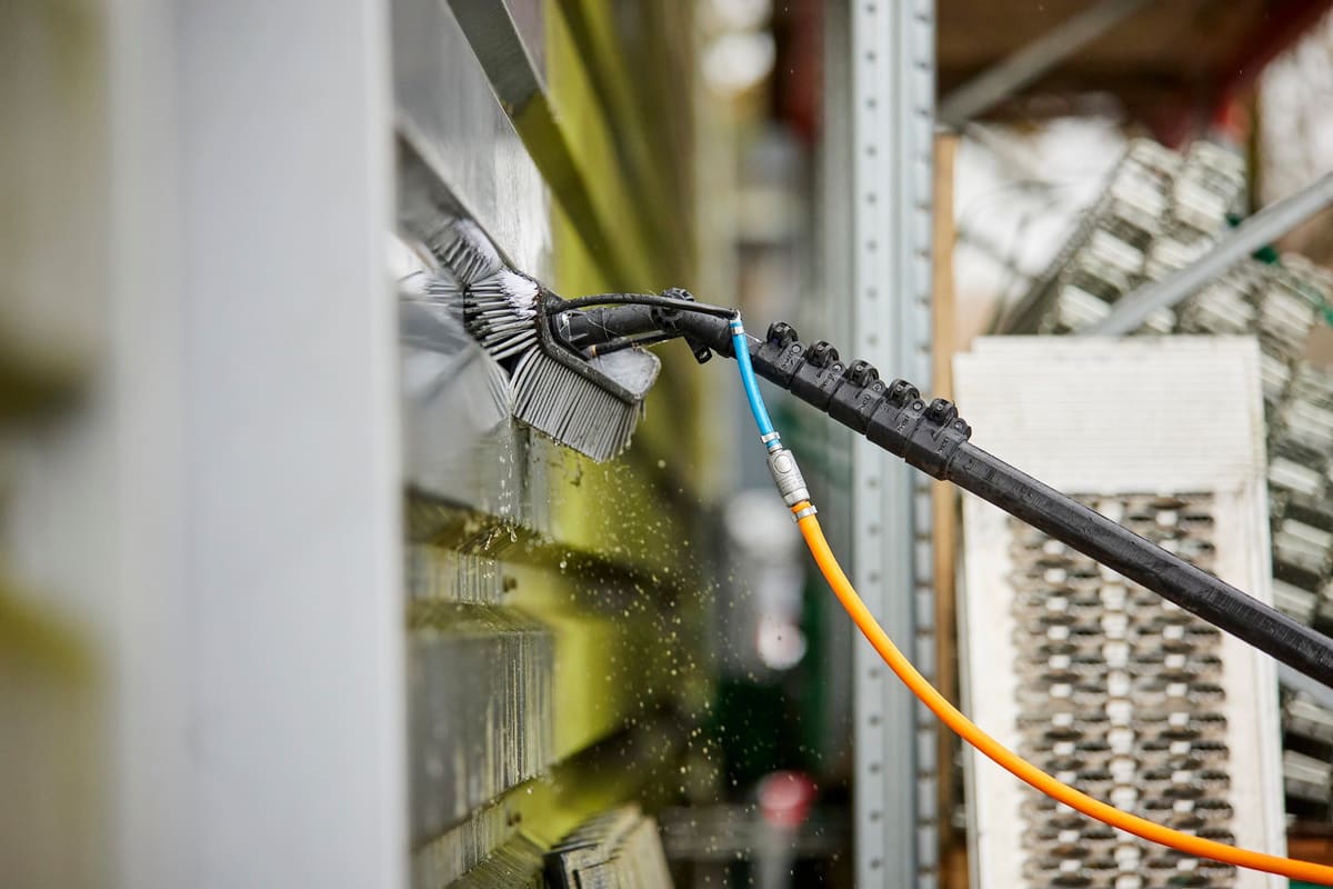 Close-up van een reinigingsborstel die algenaanslag van een gevel verwijdert