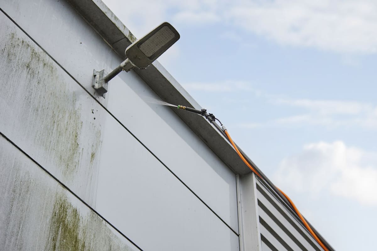 Gevel diagonaal voor de helft gereinigd, met een scherpe scheidingslijn tussen schoon en vuil