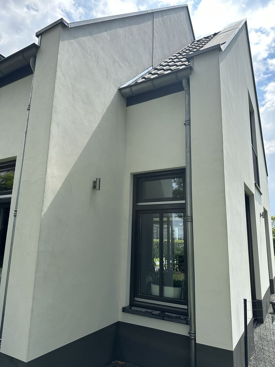 Dezelfde moderne stucwoning met een schone gevel na reiniging