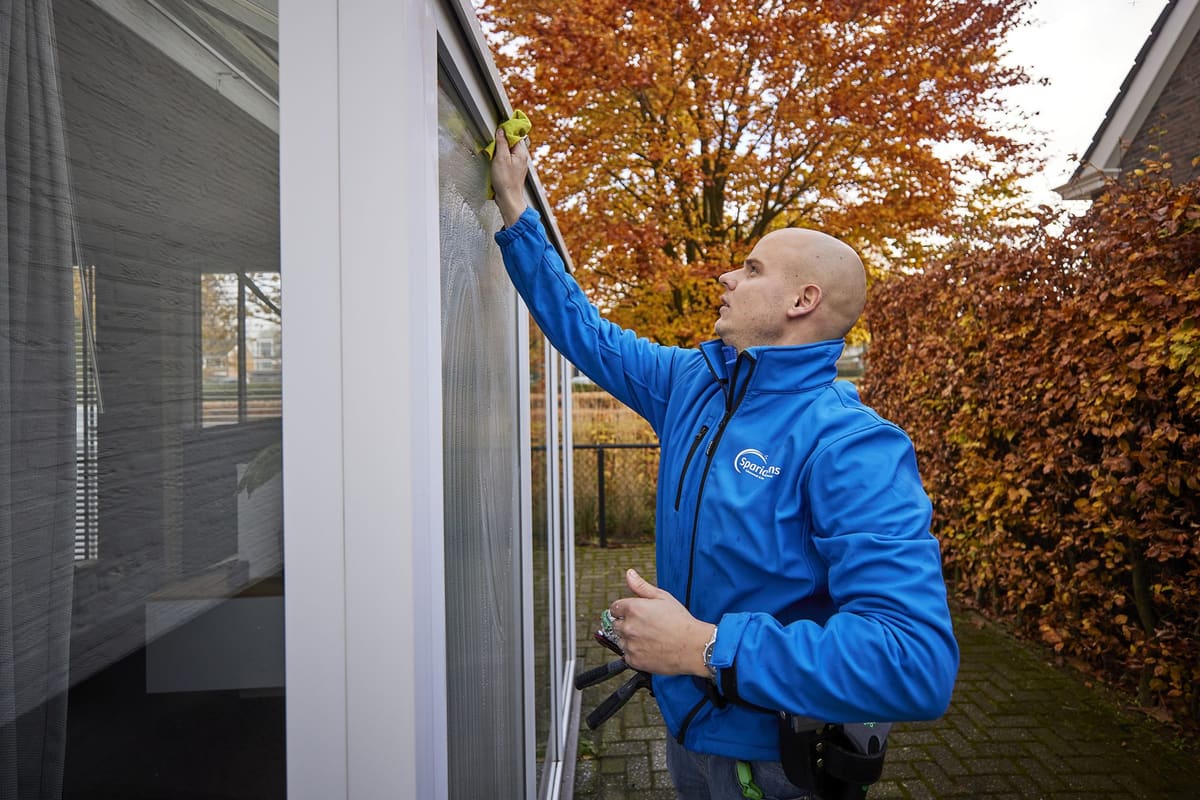 Medewerker van Sparidaens die bij een particuliere woning de kozijnen en ramen reinigt