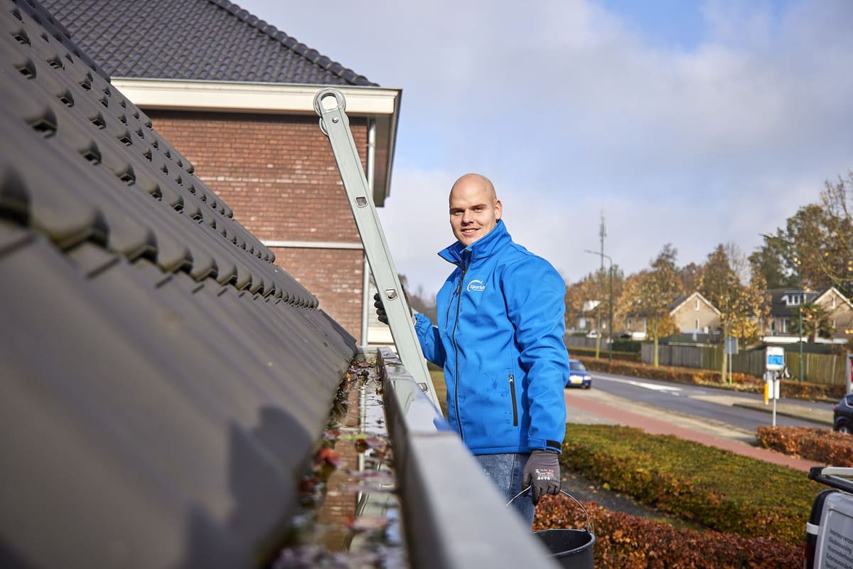Medewerker van Sparidaens aan het werk bij het reinigen van een dakgoot